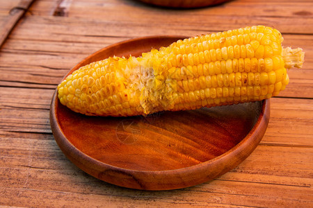 木盘上的新鲜甜玉米已经被孩子咬断了注图片