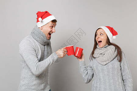 穿着红色圣诞帽灰色毛衣围巾有趣的情侣女孩拿着茶杯背景图片