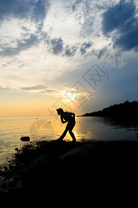 女人在日落时把石头扔进水里为了一图片