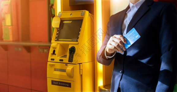 拿着信用卡的商人在自动取款机上提取现金ATM图片