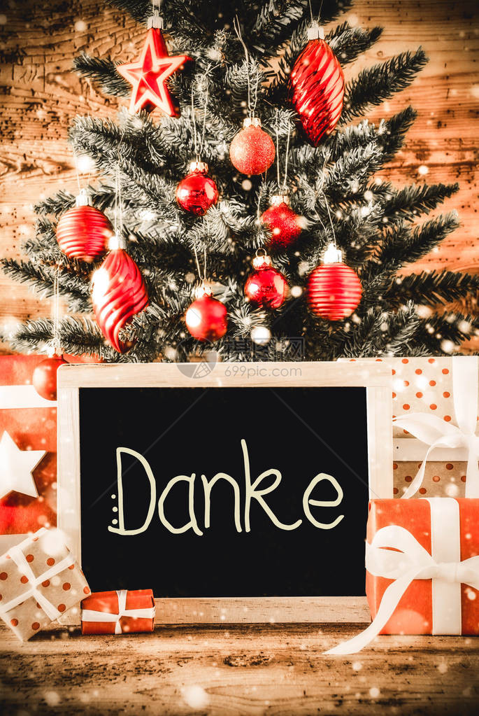 黑板与德国Danke意味着谢与圣诞树球装饰品的垂直的圣诞树雪花木制背景上图片