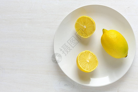 白色盘子上半个柠檬旁边的一整片柠檬有白色背图片