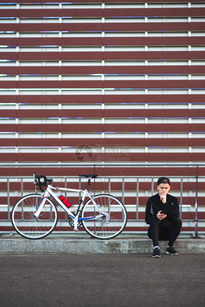 从事黑暗运动的年轻人在酒红色条纹背景上骑着自行车图片