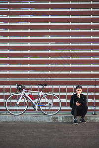 从事黑暗运动的年轻人在酒红色条纹背景上骑着自行车图片