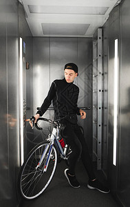一个年轻人骑着自行车在电梯里的画像骑自行车的人在一楼的电梯里放图片