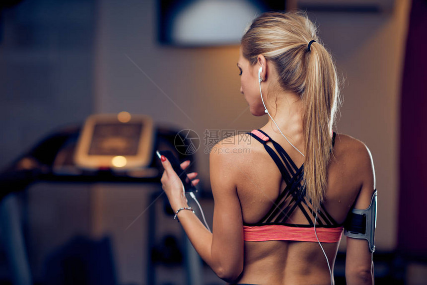 运动妇女站在健身房里时使用智能手机图片