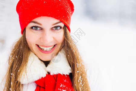 一个有雀斑的女孩微笑着的特写脸戴红帽子和围巾的女孩看着镜头图片