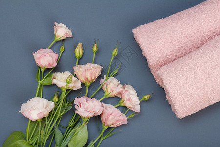 软毛巾和粉红色玫瑰花束在灰色背景图片