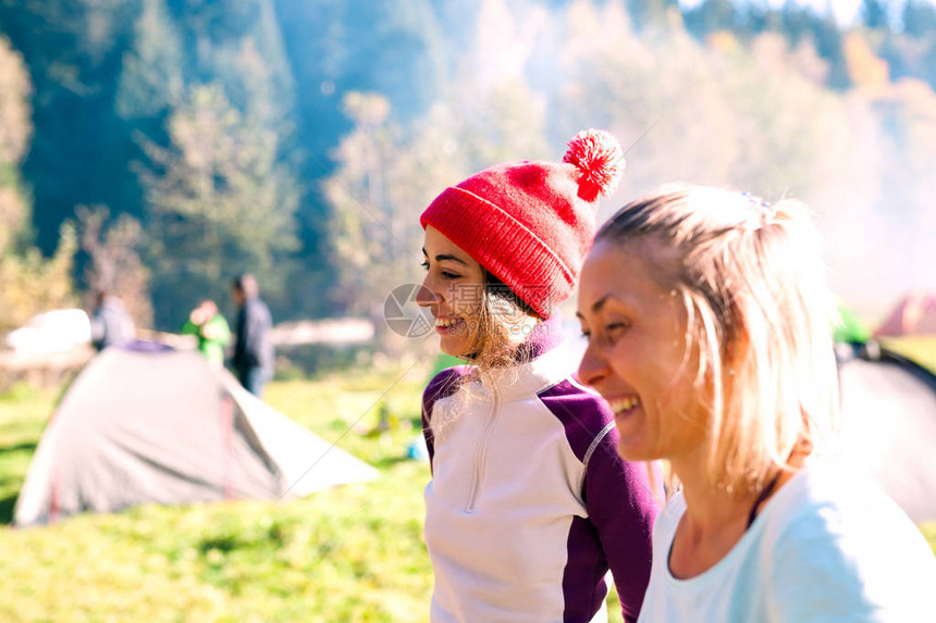 露营地的两名妇女朋友一起旅行女孩们站在帐篷附近露天音乐节在绿色图片
