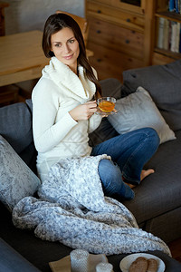 穿着毛衣的年轻美女在家灰色沙发上放图片