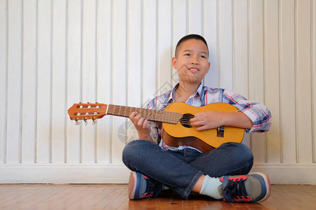 亚洲儿童男孩在家弹吉他尤克里儿童休闲活动图片