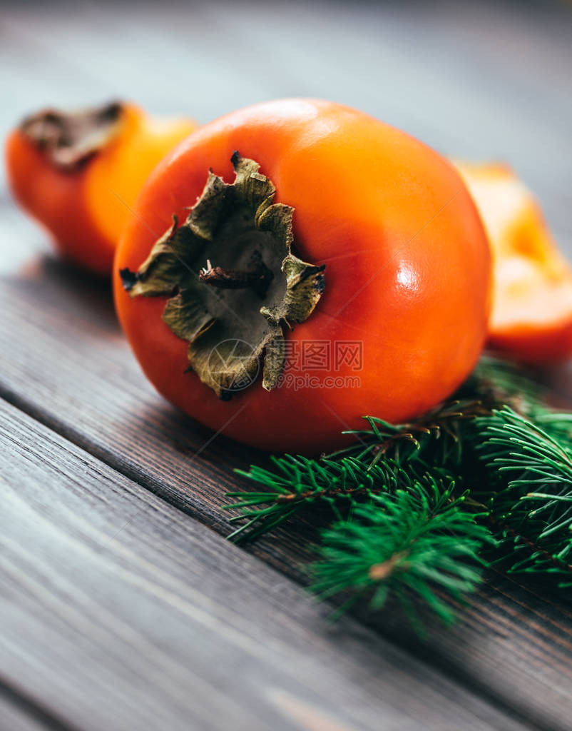 在一张木桌的背景上的明亮多汁的柿子冬季水果图片