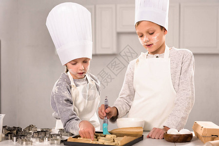 儿童集中在围裙中在厨房烘图片
