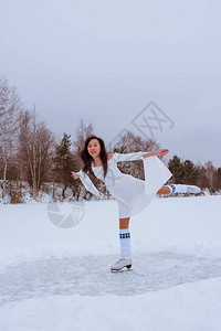冬天在户外穿着白色连衣裙滑冰的亚洲女孩图片