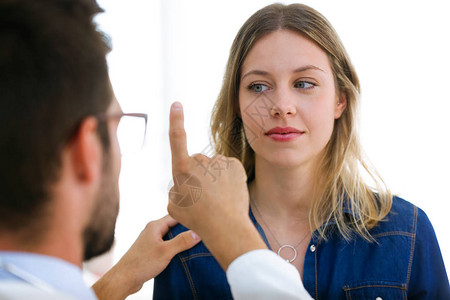 有吸引力的男医生眼科医生在现代诊所检查美丽的年轻女子的视力图片