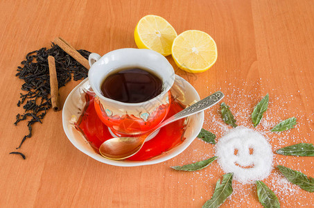 一杯木背景的茶配柠檬糖和干茶图片