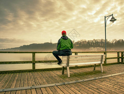 男人坐在海桥上的长椅上看着地平线图片