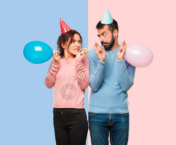 配有气球和生日帽子手指交叉并祝愿粉色和蓝色背景最背景图片