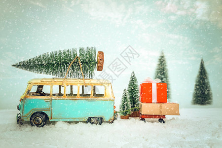 老式圣诞快乐明信片背景微型古董车在下雪的冬季的屋顶上携带圣诞树和礼图片