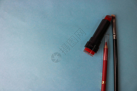 红色时尚的lipourlipad和荧光笔唇线笔和刷子在美容桌的蓝色背景上进行化妆美容指导背景图片