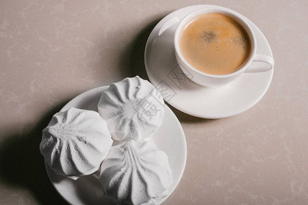 一杯新鲜的咖啡美式咖啡和三个美味的甜点白色棉花糖图片