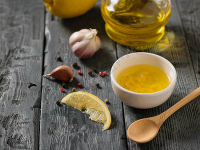 含大蒜和柠檬的橄榄油在黑桌子上的白碗里盛装食物沙背景图片