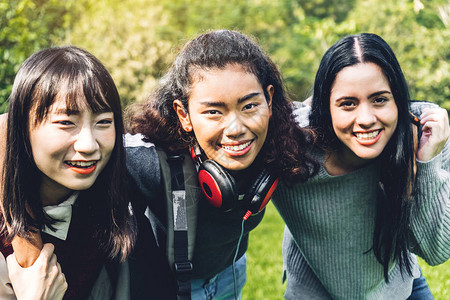 一群微笑的国际学生或青少年在大学公园里站在一起拥抱教图片