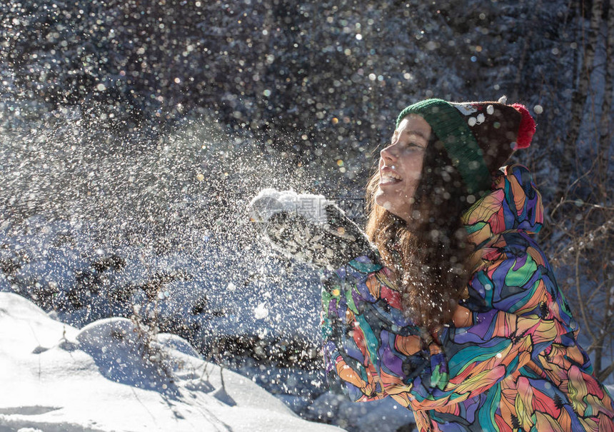 美丽的冬季女孩在寒冷的冬季公园吹雪户外飞舞的雪花晴天背光快乐美丽的年轻女子在图片