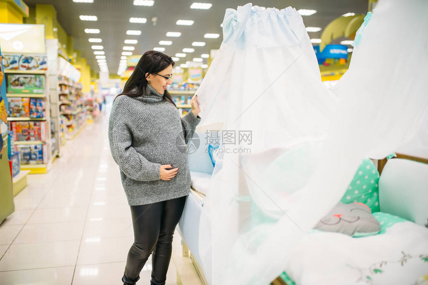孕妇在商店中选择婴儿床未来母亲在新图片