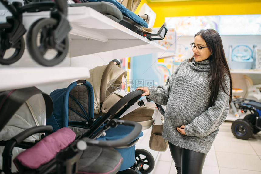 孕妇在新生儿用品店未来的母亲为她的孩图片