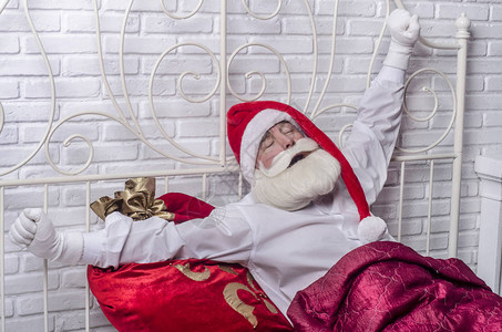 带着一包礼物的红色睡前红帽圣诞老人醒了图片