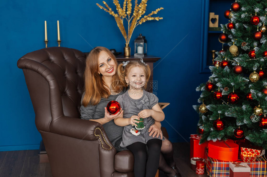 妈和女儿坐在新年房的皮椅上带着圣诞树图片