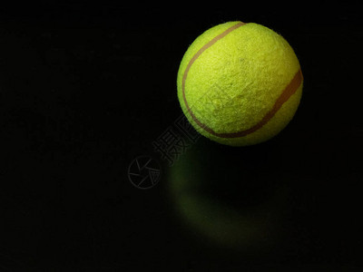 一个黄绿色的网球在暗黑光滑的地表背景上在温布尔登锦标赛中首先获得金图片
