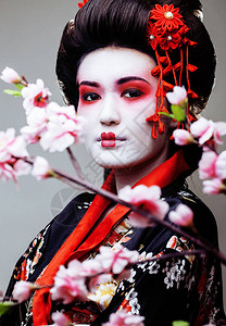 樱花中年轻漂亮的艺妓穿着黑色和服图片