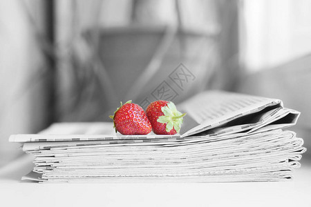 一堆报纸和草莓带有标题和文章以及新鲜水果的每日期刊多图片
