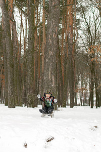 小男孩享受雪橇骑雪橇的游戏男孩在滑雪下山时图片