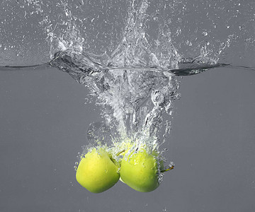 灰色背景下苹果掉入水中图片