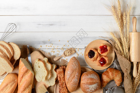 白木背景的自制面包或小圆面包羊角面包和烘焙配料早餐食品概念顶视图片