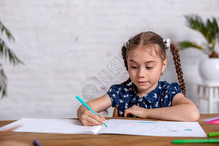 桌上的灵感小女孩用蜡笔画或做家庭作业在小学读图片