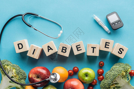 由配有医疗设备和蓝底水果的木制立方体组成的糖尿病字母背景图片