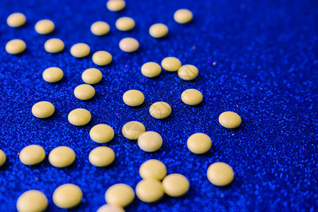 小黄橙色美丽的药丸维生素药物蓝色背景的抗生素质地图片