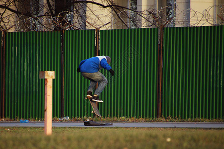 滑板手在绿色栅栏旁的滑板上弹跳图片