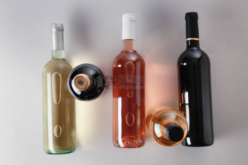 灰色背景中装有不同种类葡萄酒的瓶子图片