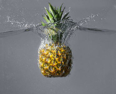 灰色背景下菠萝落入水中图片