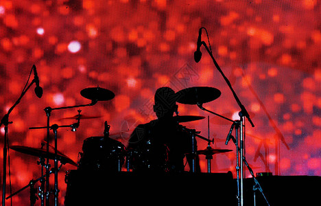 音乐会里的鼓手的轮廓与后面的红色图图片