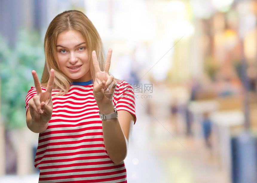 身处孤立背景的年轻caucasian女人微笑着看摄影机显示手指在做胜图片