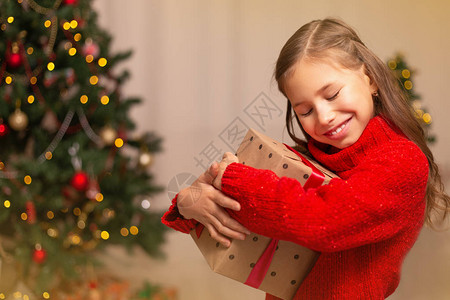 可爱的小女孩带着礼物盒在家里的圣诞树附近节日快图片