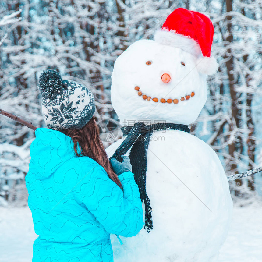 女人在寒冷的冬日概念中堆雪人图片