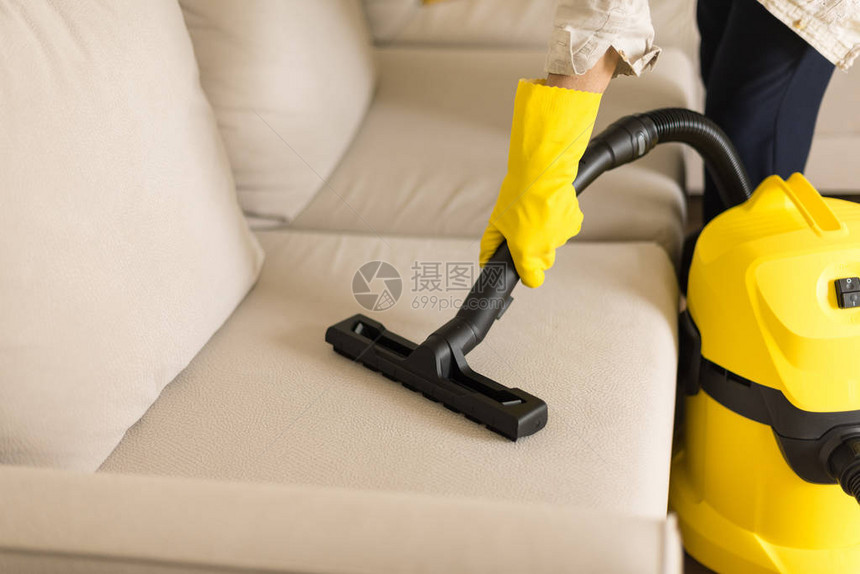 女人用黄色真空吸尘器清洁沙发复制空间图片