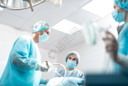 中年医生穿着无菌袍进行外科手术的侧视图图片